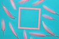 blue background with pink frame as copy space, around the frame pink feather, creative art design, dream space