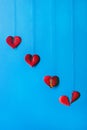 On a blue background, red hearts hang on strings