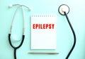 On a blue background, a stethoscope and a white notepad with the words EPILEPSY.