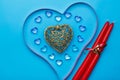 On a blue background, there is a heart of transparent pebbles in the shape of hearts in the middle of a gold heart and a Royalty Free Stock Photo