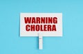 On a blue background, there are pills and a business card with the inscription - WARNING CHOLERA