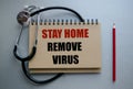 A blue background on which lies a notepad with the inscription STAY HOME REMOVE VIRUS. Top view, floor plan. Stationery,