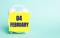 On a blue background - a white alarm clock with a yellow sticker for notes with the text FEBRUARY 04