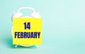 On a blue background - a white alarm clock with a yellow sticker for notes with the text FEBRUARY 14