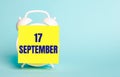 On a blue background - a white alarm clock with a yellow sticker for notes with the text SEPTEMBER 17 Royalty Free Stock Photo