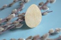 On a blue background are willow branches and one paper egg. Beautiful composition for Easter. Crafts for Easter with Royalty Free Stock Photo
