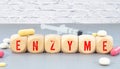 On a blue background, wooden blocks with the word ENZYME and pills. Medical concept.