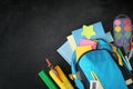 Blue backpack and different stationery on blackboard, flat lay with space for text. Back to school Royalty Free Stock Photo