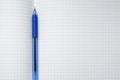 A blue ball pen lying on a blank checkered school notebook sheet , paper with copy space Royalty Free Stock Photo