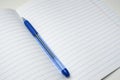 A blue ball pen lying on a blank lined school notebook sheet , paper with copy space Royalty Free Stock Photo