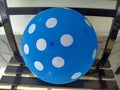 A blue balloon with a white circle pattern sits on a black metal chair