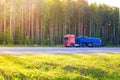 Blue barrel truck with dangerous cargo is parked on the side of a forest road