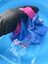 Hand wash napkins in a blue basin. female hand in black glove washes clothes Royalty Free Stock Photo