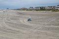 A blue beach cart and tote bags abandoned on a large deserted sandy beach