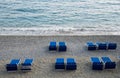 Blue beach relaxing chairs on an empty sandy coast.