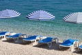 Blue beach umbrellas and chaise for relax on sea resort. Summer vacations and travel for seaside. Paid service on comfort beaches