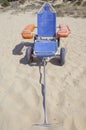 Blue beach wheelchair on sand ready to use Royalty Free Stock Photo