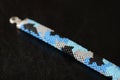Blue beaded bracelet camouflage coloring on a dark background Royalty Free Stock Photo