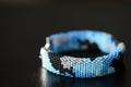 Blue beaded bracelet camouflage coloring on a dark background Royalty Free Stock Photo