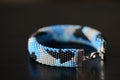 Blue beaded bracelet camouflage coloring on a dark background Royalty Free Stock Photo