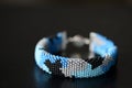 Blue beaded bracelet camouflage coloring on a dark background Royalty Free Stock Photo