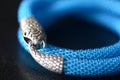 Blue beaded necklace with snake head lock on a dark background