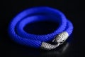 Blue beaded necklace with snake head lock on a dark background