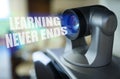 A blue beam glows from the projector inside which is the inscription - Learning Never Ends Royalty Free Stock Photo