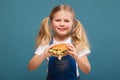 Adorable cute little girl in white shirt and jean jumpsuit with hamburger Royalty Free Stock Photo