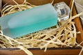 Blue, beautiful, glass bottle with cologne, toilet water, perfume in a wooden homemade box with dried straw