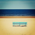 Blue bench on the empty beach - vintage photo. Picnic bench and spring seascape - retro filter. Royalty Free Stock Photo