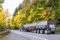 Blue big rig classic semi truck transporting pumpkin harvest in long bulk semi trailer driving on the winding mountain road with Royalty Free Stock Photo