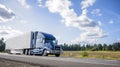 Blue big rig semi truck with grille guard trabsporting frozen cargo in refrigerator semi trailer with skirt spoiler running on the Royalty Free Stock Photo