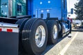 Blue big rig semi truck tractor with new wheels tires on alloy rims standing on the truck stop parking lot beside with another Royalty Free Stock Photo