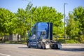 Blue big rig semi truck tractor running on the green city street road for pick up the loaded semi trailer for next delivery Royalty Free Stock Photo