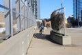 A blue bike parked on a sidewalk on a freeway overpass surrounded by office buildings and blue sky