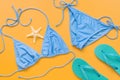 Blue bikini swimsuit, turquoise flip flops and starfish on a yellow background, flat lay. Women`s beach accessories. Travel Royalty Free Stock Photo