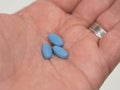 Blue pills for erectile dysfunction held in palm of hand.