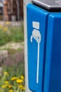 Blue bin outdoors in a street with hand with cane