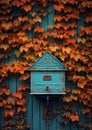 a blue bird house on a wall covered in leaves