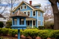 a blue birdhouse in the yard of a colonial revival house