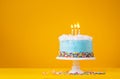 Blue Birthday Cake with three Candles over a yellow Background Royalty Free Stock Photo