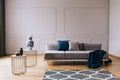 Blue blanket and pillows on grey comfortable sofa in designed living room interior with wooden floor and white wall Royalty Free Stock Photo