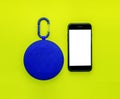 Blue bluetooth speaker and mobile phone or smartphone mock up on yellow background, business technology concept
