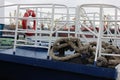 Blue boat deck with white fence, red life ring and thick jute rope