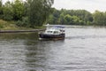 Blue boat floating on the river. Trees grow on the banks of the river. Fork of the river. Landscape, summer day.