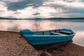 The blue boat moored to the lake under stormy clouds