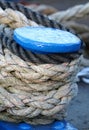 Blue boat mooring post covered with securing ropes.