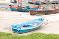 Blue boat on the sandy shore in the background of fishing boats Royalty Free Stock Photo