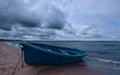 Blue boat on a shore of the sea with stormy clouds on the sky. Royalty Free Stock Photo